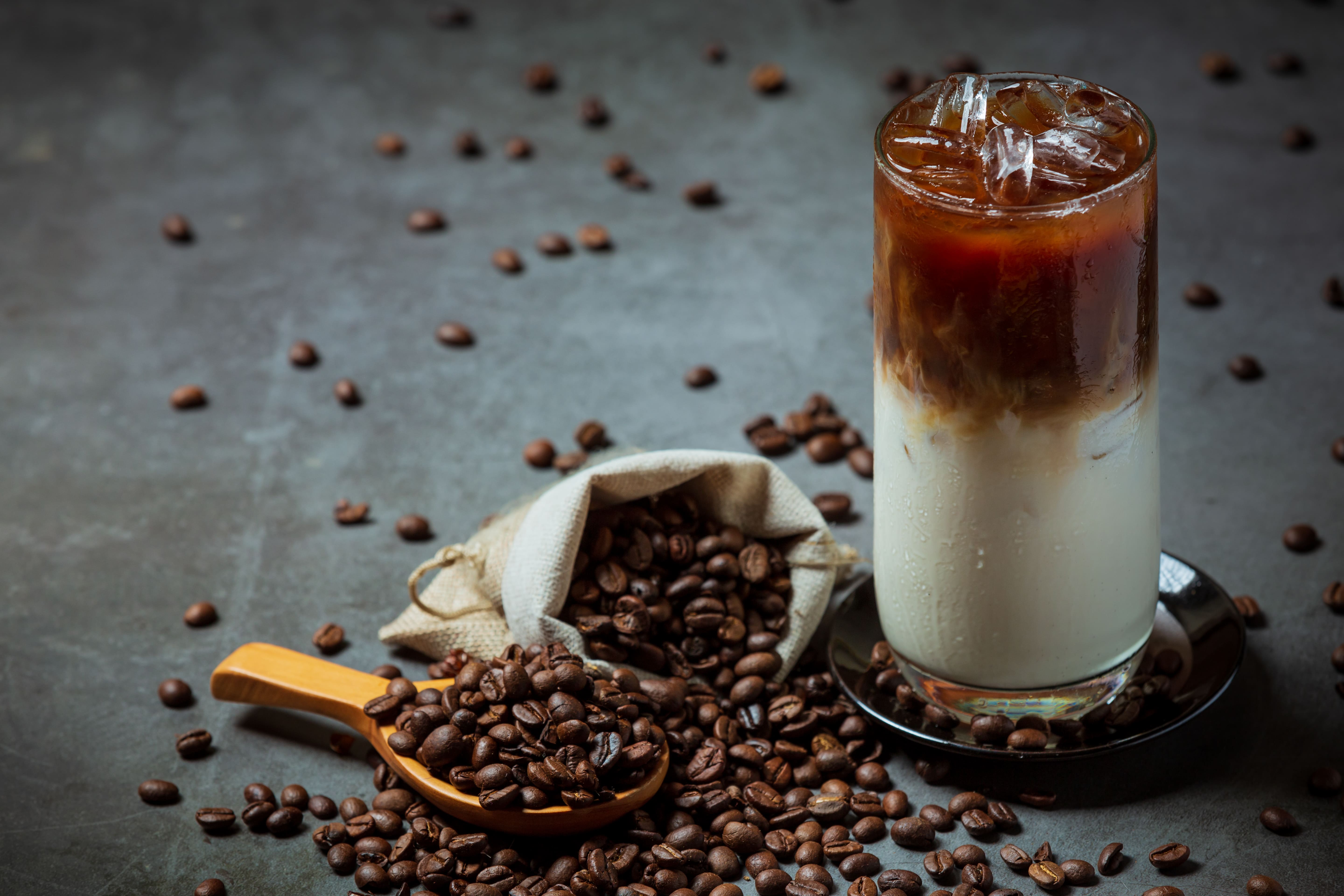 Iced latte with coffee beans in a spoon